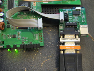 Photo of adapter board with a nine pin serial cable, null modem, and gender changer attached.